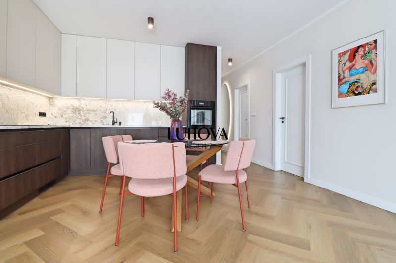 Kitchen corner in a 3-room apartment with a table, pink chairs, and a wooden decor floor.