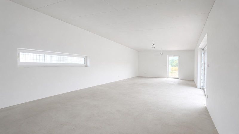 Empty room in a family house with white walls and large windows.