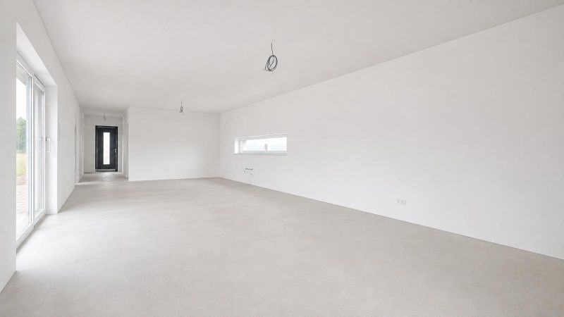 A spacious white room with large windows and a light floor in a family house.