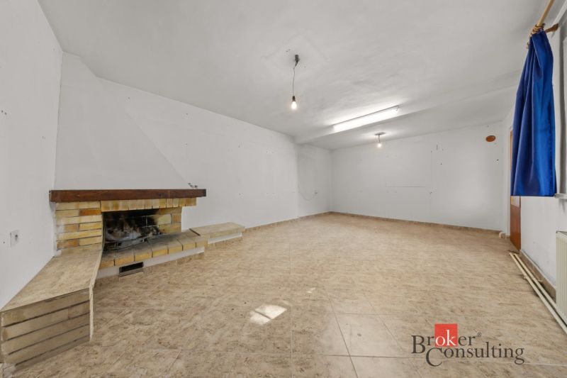 A spacious room with a fireplace and tiles in a family house.