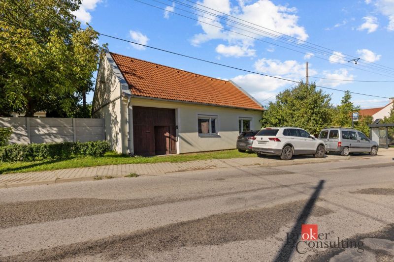 A family house in Budmerice with a red roof, cars parked in front of the house.