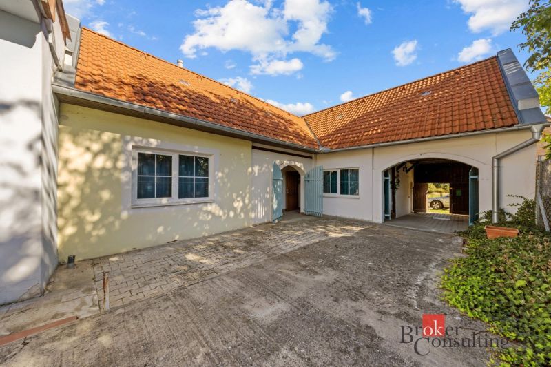 A family house in Budmerice with a sloped roof and a paved courtyard.