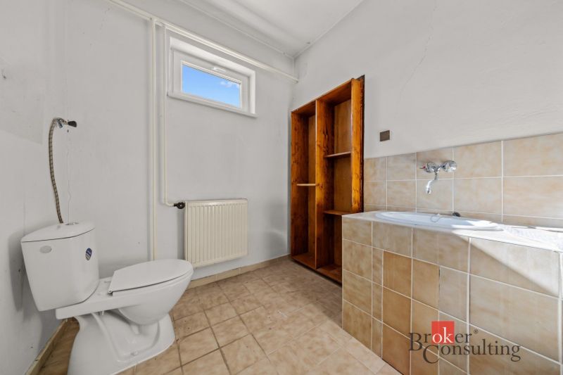 Bathroom in a family house with a toilet, bathtub, and ceramic tiles.