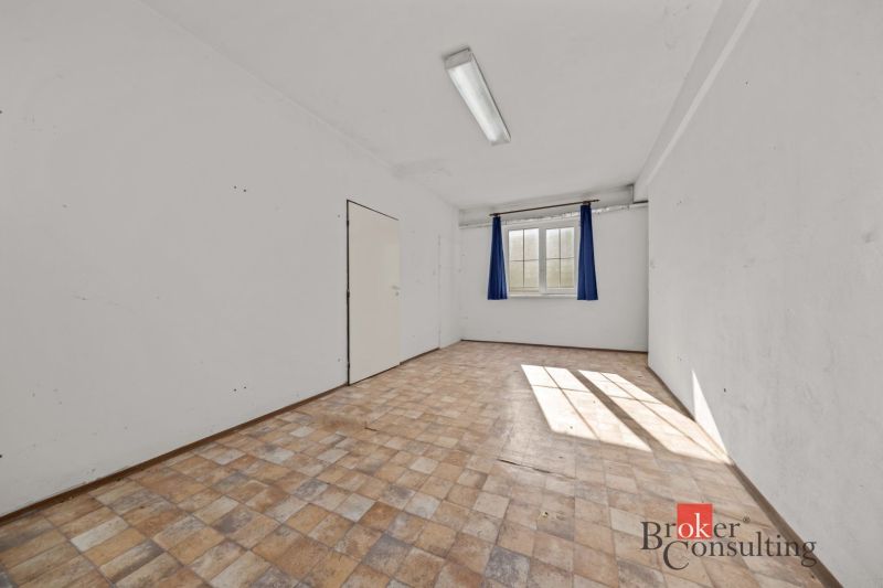 A bright room in a family house with a window and a wooden-patterned floor.