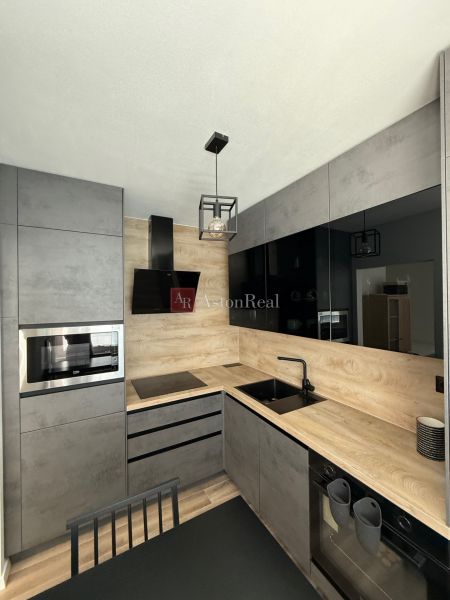 Kitchen unit with a microwave and a sink, floor with wooden decor, 1-room apartment.