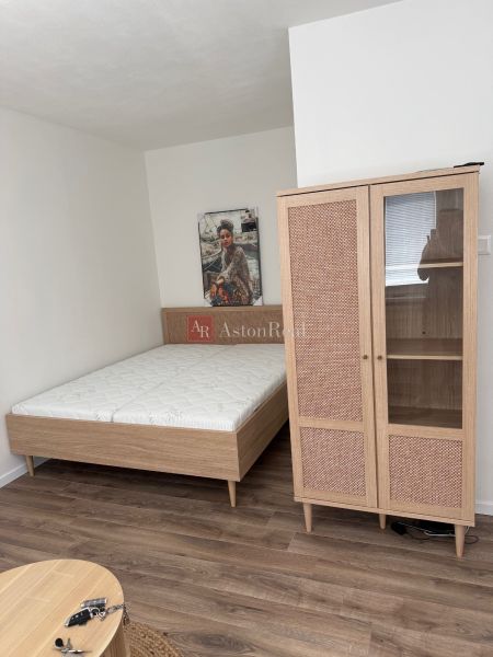 Bed, wardrobe, and floor with wood decor in a studio apartment.