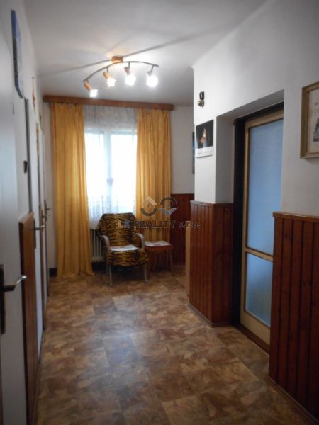 A hallway in a family house with a wooden decor floor, an armchair, and curtains.