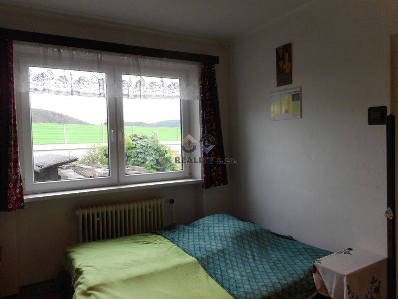 A room with a green bed, a window, and a view. The family house offers a cozy space.