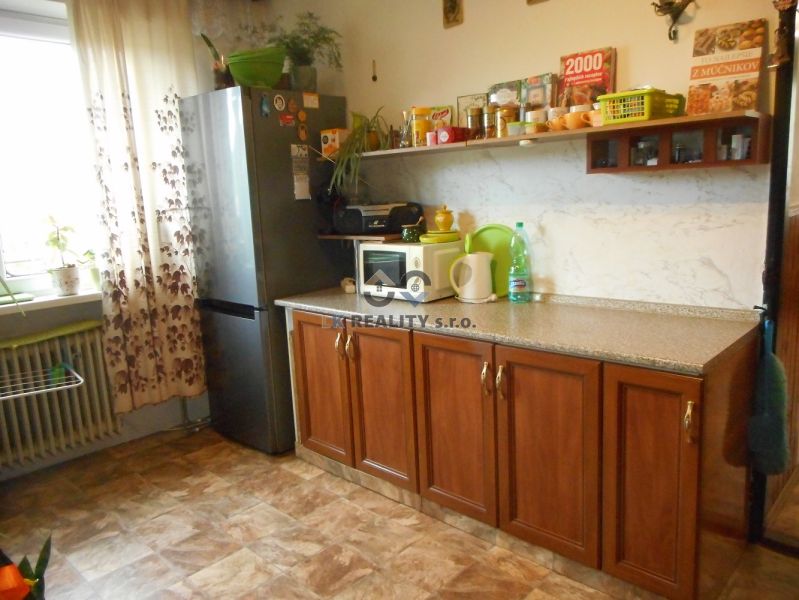 A kitchen in a family house with a refrigerator and cabinets, a floor with a wooden decor.