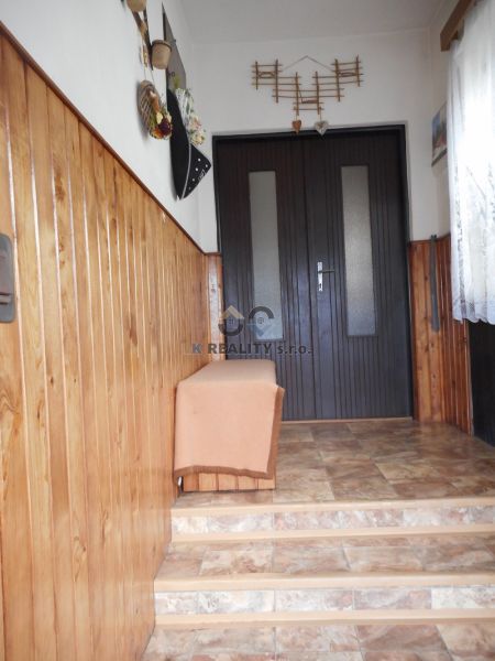 A hallway in a family house with wooden paneling and ceramic flooring.