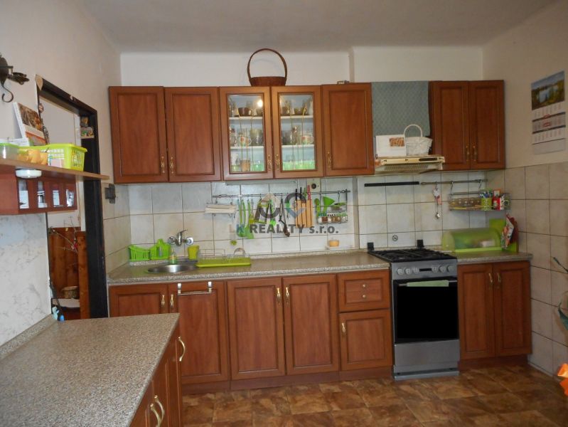 A kitchen in a family house with brown cabinets, tiles, and a gas stove.