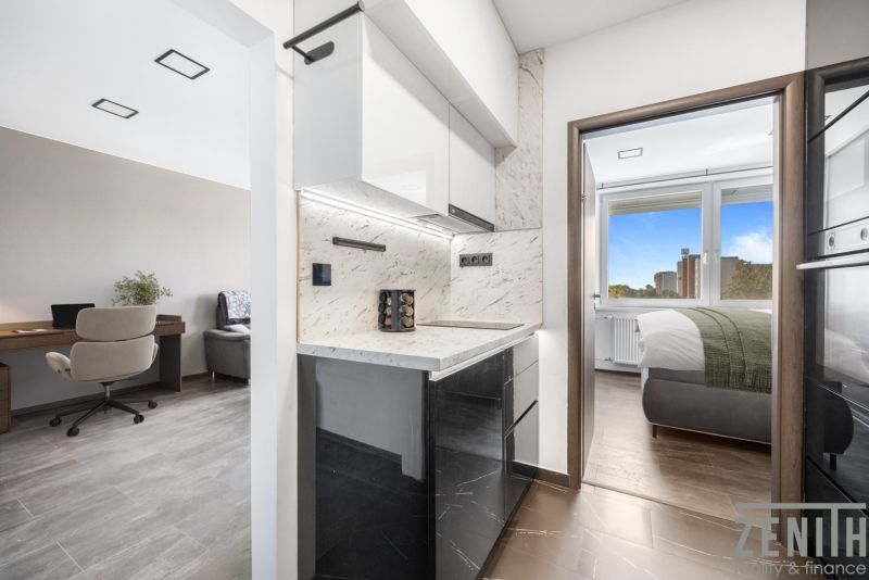 A kitchen with a marble countertop, next to a desk on a floor with a wooden decor.
