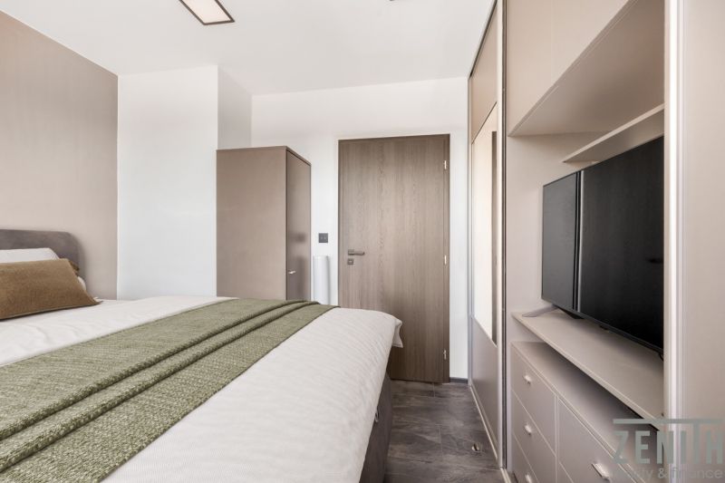 A bedroom with a bed, wardrobe, and television in a 2-room apartment.