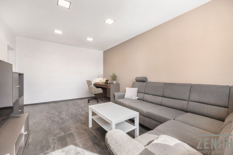 Living room with a gray sofa, a desk, and a coffee table in a two-room apartment.