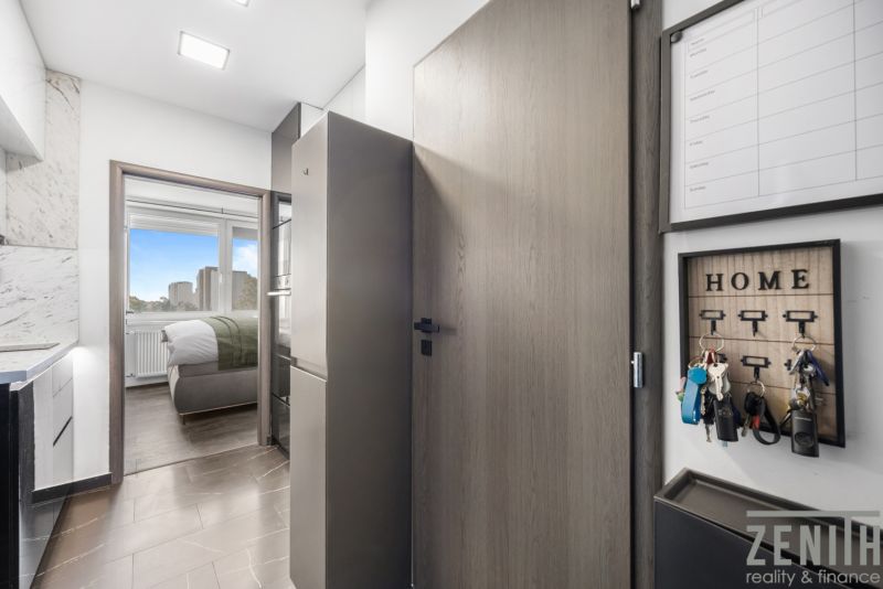 A kitchen in a 2-room apartment with a view of the bedroom, floor with a wooden decor.