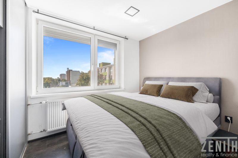 A bedroom in a 2-room apartment with a large window and a comfortable bed.