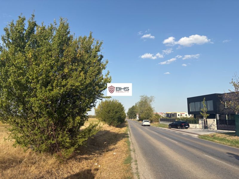 Commercial land on Šenkvická Road in Pezinok with an asphalt road and greenery.