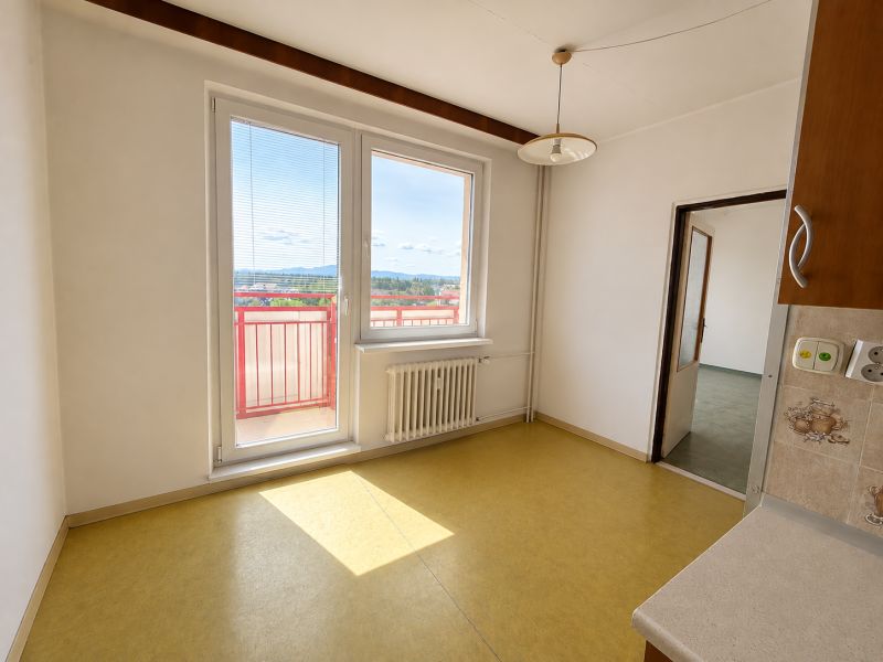 A white kitchen interior with a large window and yellow floor in a 3-room apartment.
