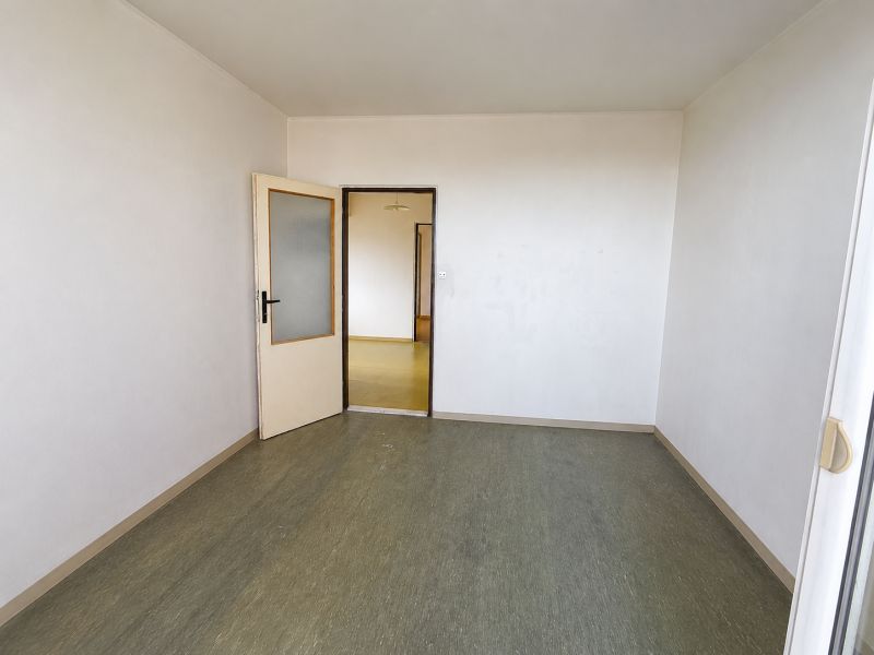 An empty room in a 3-room apartment with open doors and a green floor.