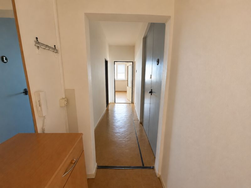 A hallway in a 3-room apartment with a wall-mounted telephone and laminate flooring.
