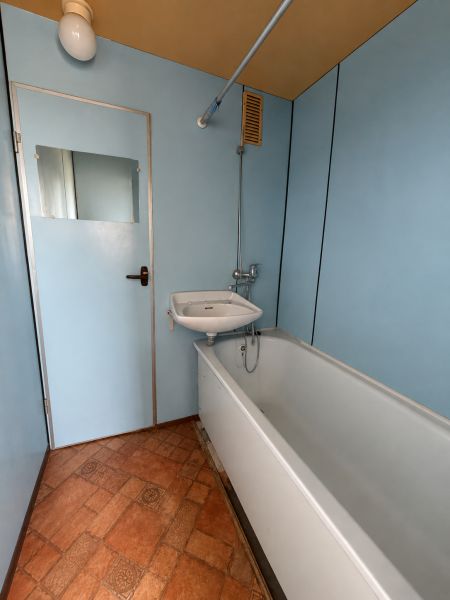 Bathroom with a bathtub in a 3-room apartment, blue walls and tiles with a pattern.