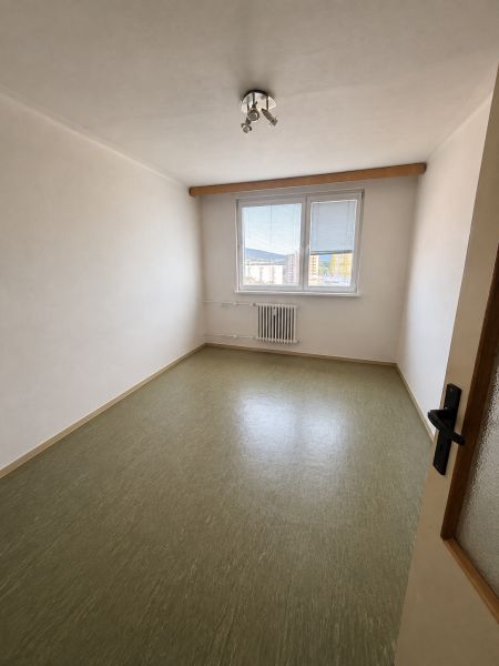 An empty room in a 3-room apartment with a window and a wooden decor floor.