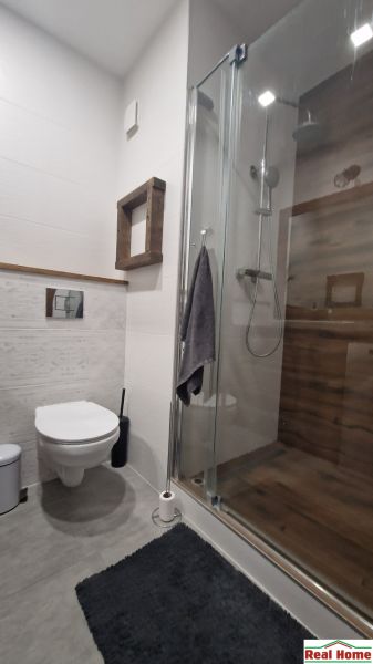 Bathroom with toilet and shower in a 2-room apartment, floor with wooden decor.