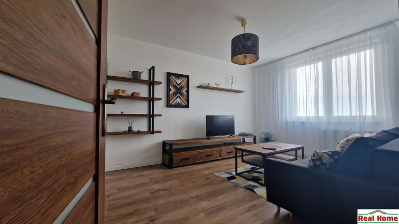 Living room with TV, shelves, and wooden decor flooring in a 2-room apartment.
