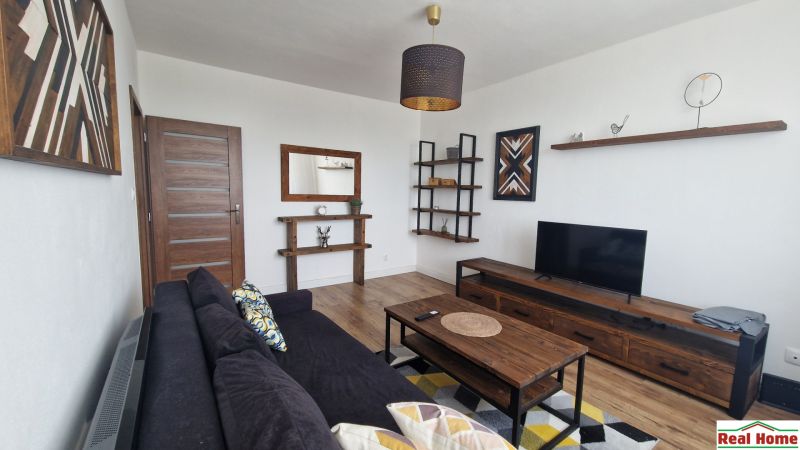 Living room with a sofa, wooden furniture, and a floor with a wood decor, 2-room apartment.