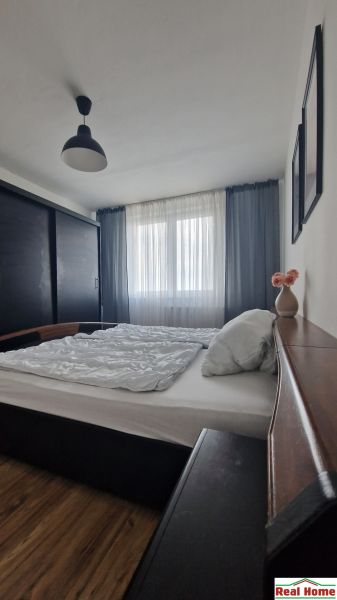 Bedroom in a 2-room apartment with a bed, a large wardrobe, and a floor with a wooden decor.
