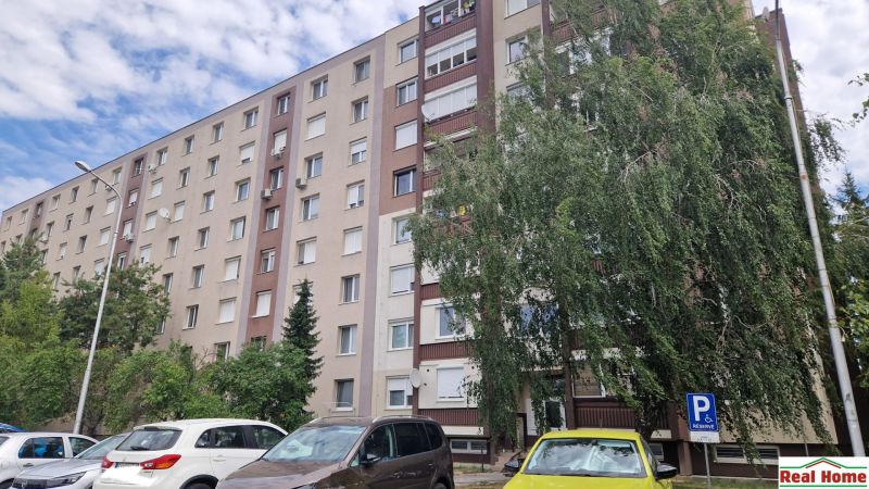 The apartment building on Železničiarska Street in Galanta shows a parking lot and greenery.
