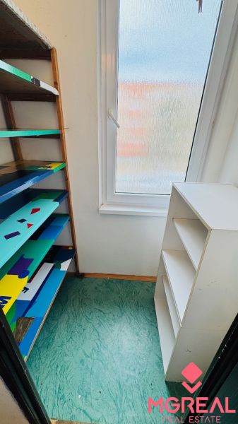 Storage space in a 3-room apartment with shelves and a window, floor with decor.