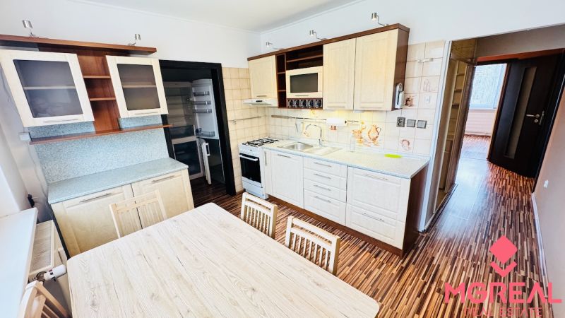 A kitchen with a dining table in a 3-room apartment with a wooden decor floor.