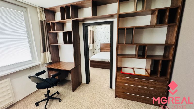 A workspace with shelves in a 3-room apartment, leading to the bedroom.