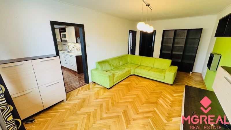 Living room with a green sofa and a wooden decor floor in a 3-room apartment.