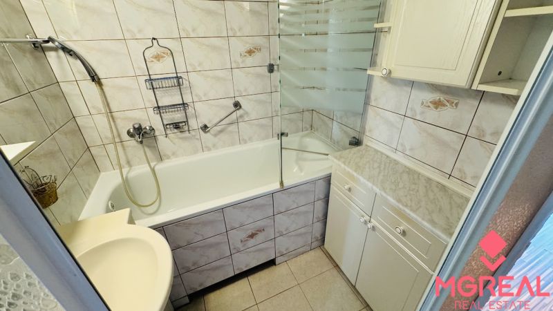 A bathroom in a 3-room apartment with a bathtub, a sink, and a cabinet.
