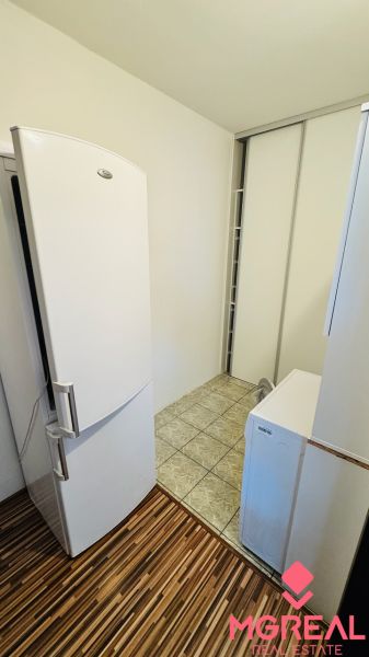 Kitchen with tiles, refrigerator, and cabinet, 3-room apartment, wooden decor flooring.