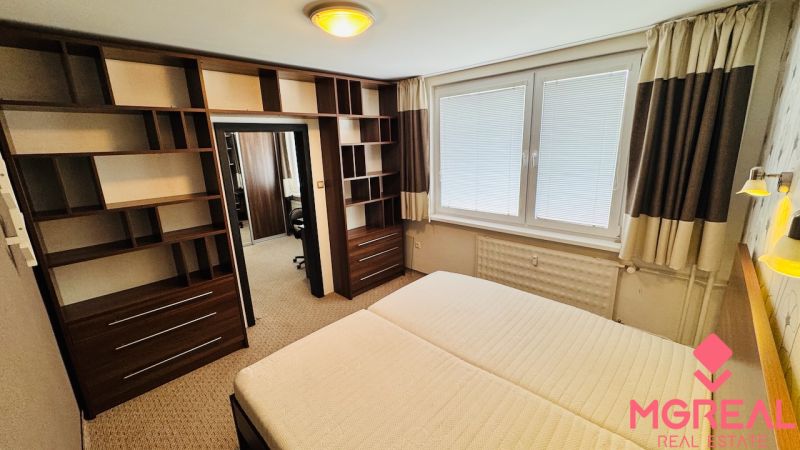 A bedroom with shelves in a 3-room apartment, equipped with a large window with blinds.