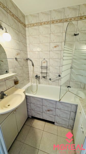 A bathroom in a 3-room apartment with a bathtub, a sink, and tiles.