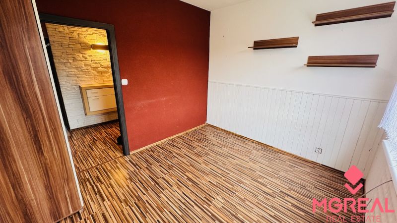A room in a 3-room apartment with a wooden decor floor and a wall in a warm color.