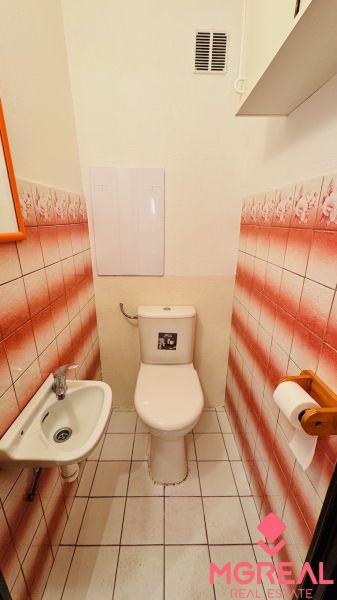 A toilet with a sink and distinctive tiles in a 3-room apartment.