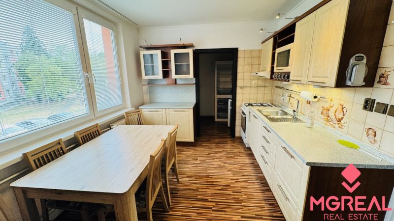 A kitchen with a wooden decor floor in a 3-room apartment, a dining table by the window.