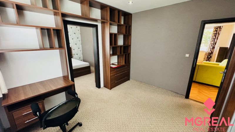 A room in a 3-room apartment with a desk, chair, and entrance to the bedroom.