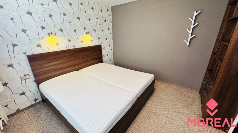 A bedroom in a 3-room apartment with simple decoration and floral patterned wallpaper.