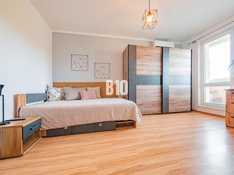 A one-room apartment with a bed, a wardrobe, and a floor with a wooden decor.
