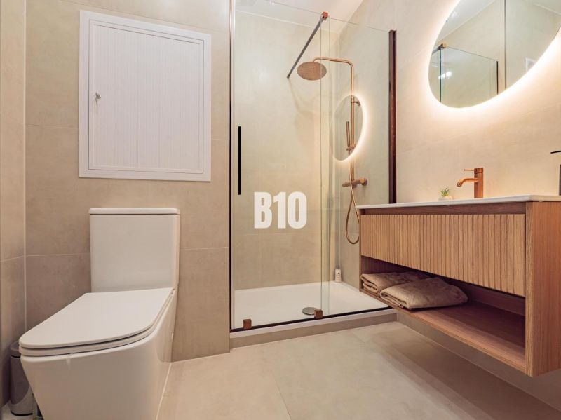 Bathroom with toilet, wooden sink, and shower in a studio apartment.