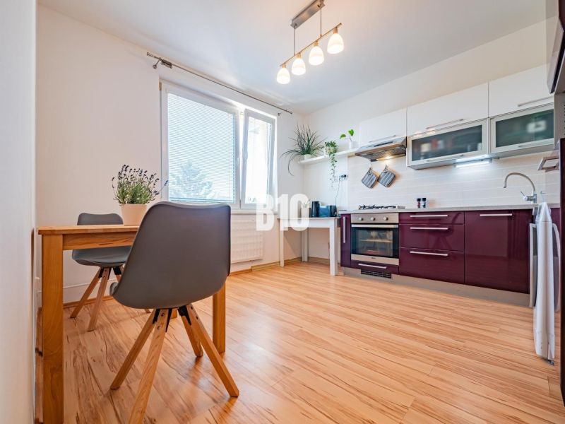 A kitchen in a studio apartment with a wooden floor decor and a dining table.