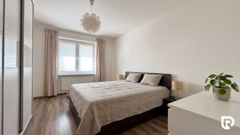 Bedroom in a 2-room apartment with a wooden decor floor and white walls.
