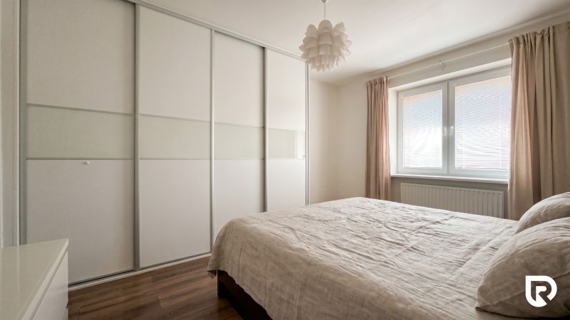 Bedroom in a 2-room apartment with a large wardrobe, bed, and floor with a wooden decor.