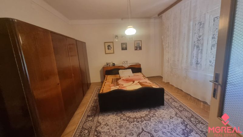 Bedroom in a family house with a bed, cabinet, carpet, and wall decorations.